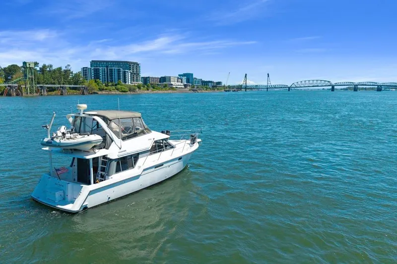Slide: The Image of 1994 Carver 370 Voyager yacht on a scenic river with cityscape and bridge backdrop. - 67