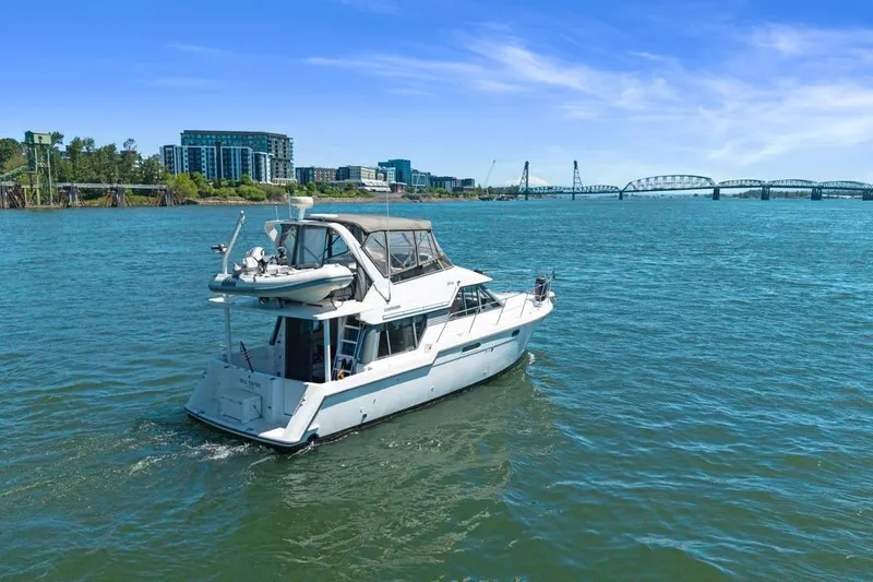 Slide: The Image of 1994 Carver 370 Voyager yacht cruising on a scenic river with a bridge in the background. - 68
