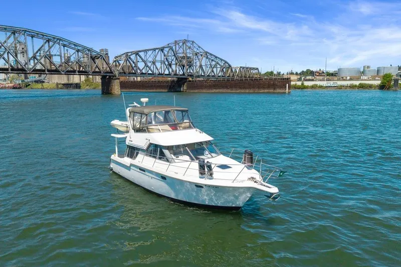 Slide: The Image of 1994 Carver 370 Voyager yacht on a river near a steel bridge under a clear blue sky. - 72
