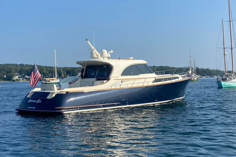 Slide: The Image of 2006 Mochi Craft 51 Dolphin yacht on calm water, displaying an American flag. - 2