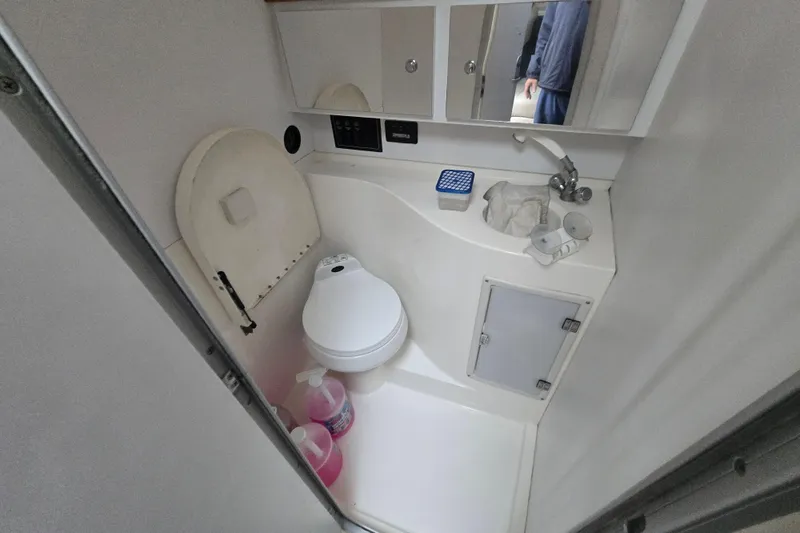 Slide: The Image of Compact bathroom in a 1998 Wellcraft 330 Coastal boat, featuring a toilet and sink. - 12