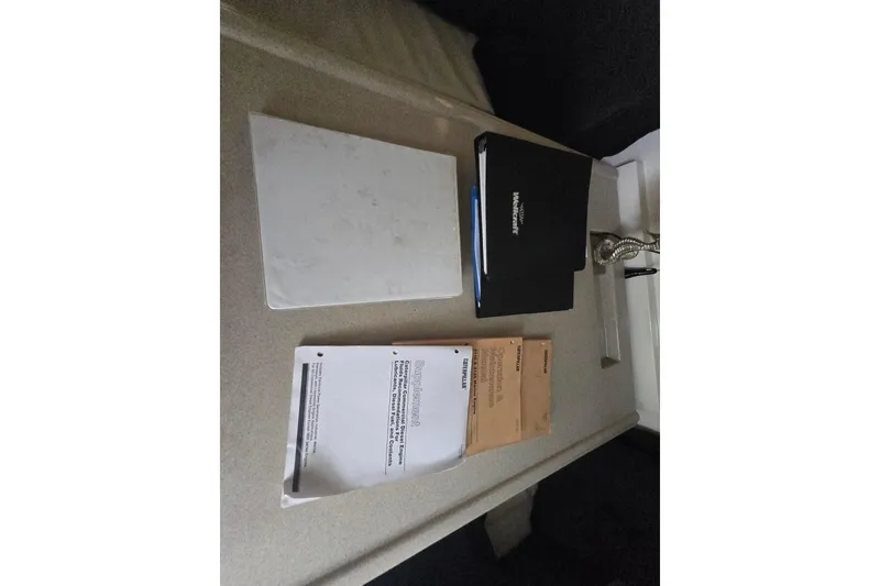 Slide: The Image of Documents and manuals for a 1998 Wellcraft 330 Coastal boat on a table. - 13