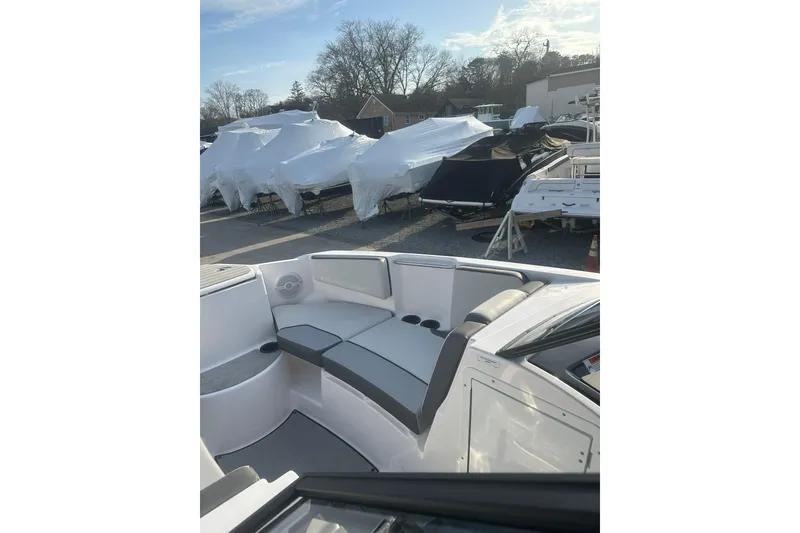 Slide: The Image of 2025 Yamaha Boats AR220 interior with sleek seating, parked among covered boats. - 18
