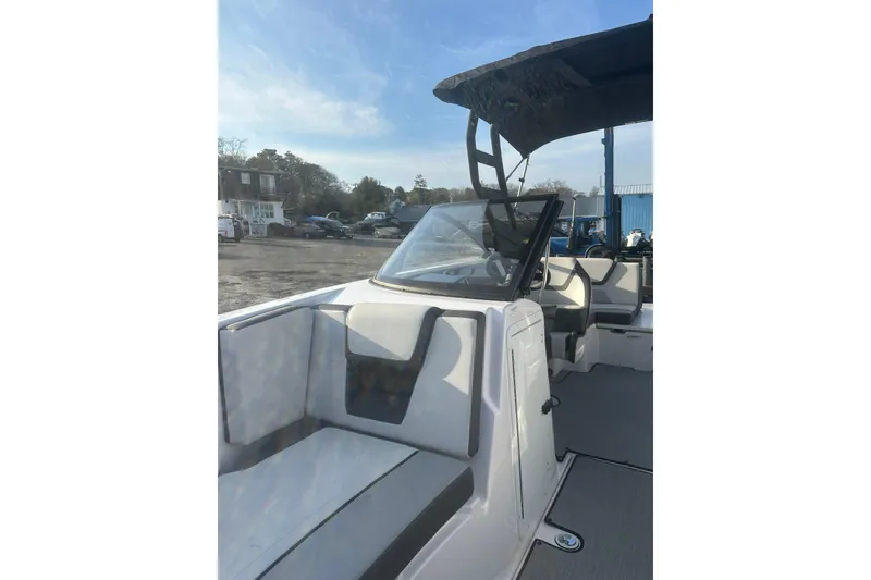 Slide: The Image of 2025 Yamaha Boats AR220 interior with seating and canopy under clear sky. - 22