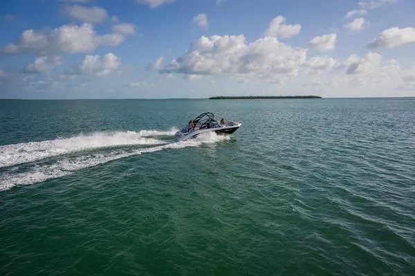 Slide: The Image of 2025 Yamaha Boats AR220 on trailer, rear view, with two people nearby under clear sky. - 5