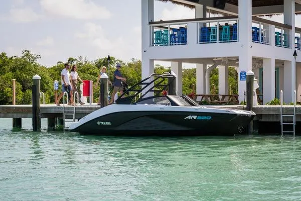 Slide: The Image of 2025 Yamaha Boats AR220 interior seating with modern design at a marina. - 7