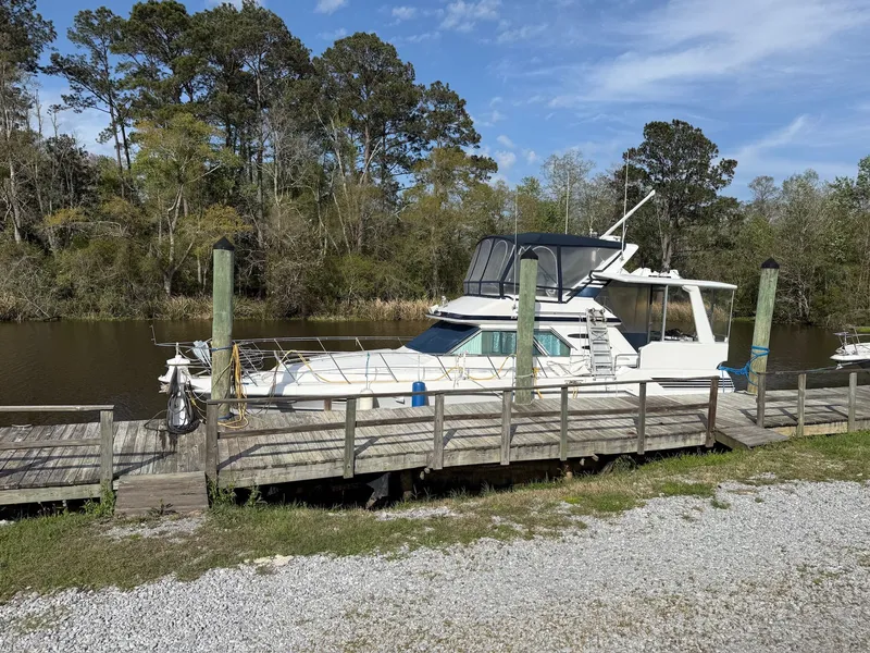 Slide: The Image of 1988 Sea Ray 415 Aft Cabin docked, surrounded by trees. - 2