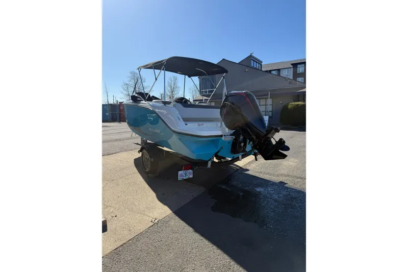 Slide: The Image of 2024 Bayliner Element M19 boat with outboard motor, parked outdoors. - 2