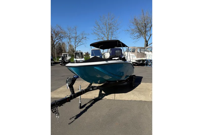 Slide: The Image of 2024 Bayliner Element M19 boat on trailer, parked outdoors under clear blue sky. - 4