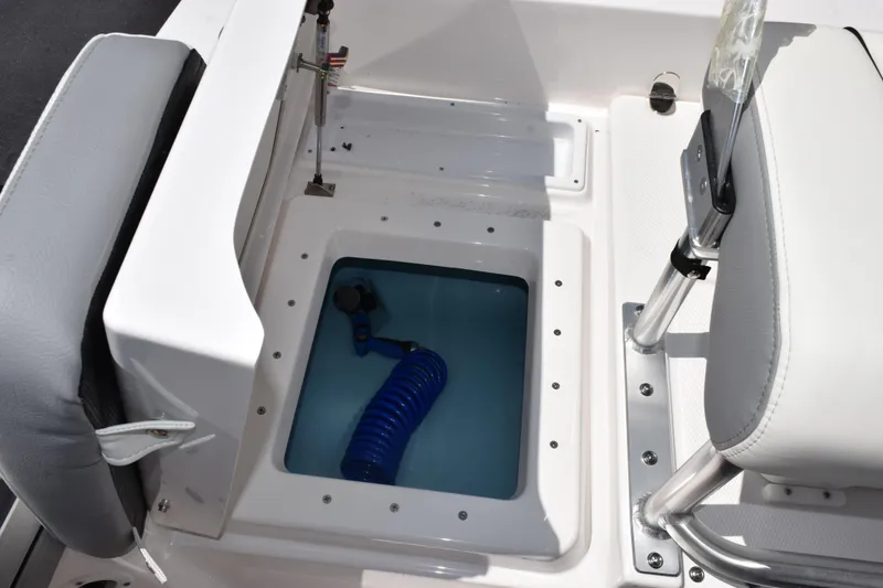 Slide: The Image of 2026 Yamaha Boats 190 FSH Sport interior storage compartment with blue hose. - 18