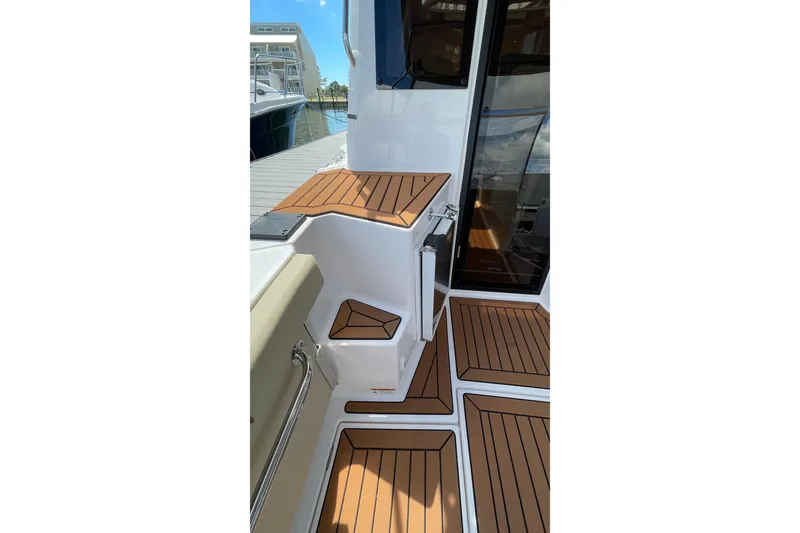 Slide: The Image of 2025 Ranger Tugs R-27 Seakeeper Ride boat deck with wood finish, docked at marina. - 11