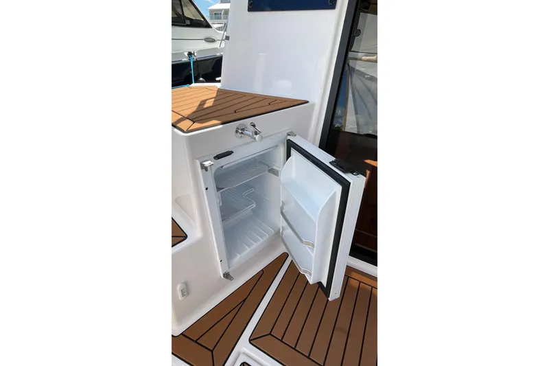 Slide: The Image of 2025 Ranger Tugs R-27 Seakeeper Ride with open onboard refrigerator, showcasing teak flooring. - 19