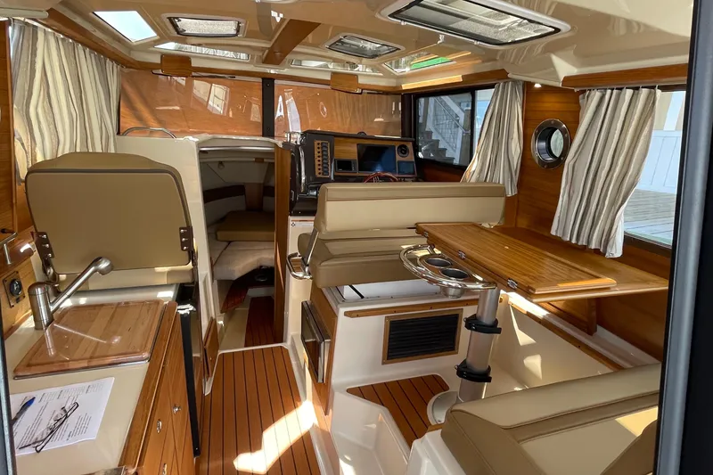 Slide: The Image of 2025 Ranger Tugs R-27 Seakeeper Ride interior with wood accents and seating area. - 21