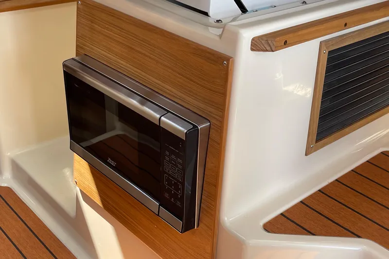 Slide: The Image of 2025 Ranger Tugs R-27 Seakeeper Ride interior with built-in microwave and wood accents. - 32