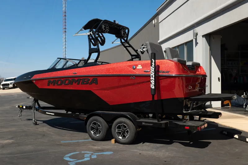 Slide: The Image of 2025 Moomba Max boat in red, parked on a trailer outside a building. - 3