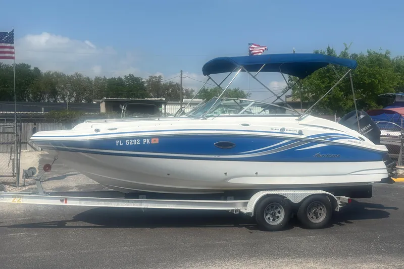 Slide: The Image of 2013 Hurricane SunDeck 2200 DC OB boat on trailer, blue and white design, parked outdoors. - 10