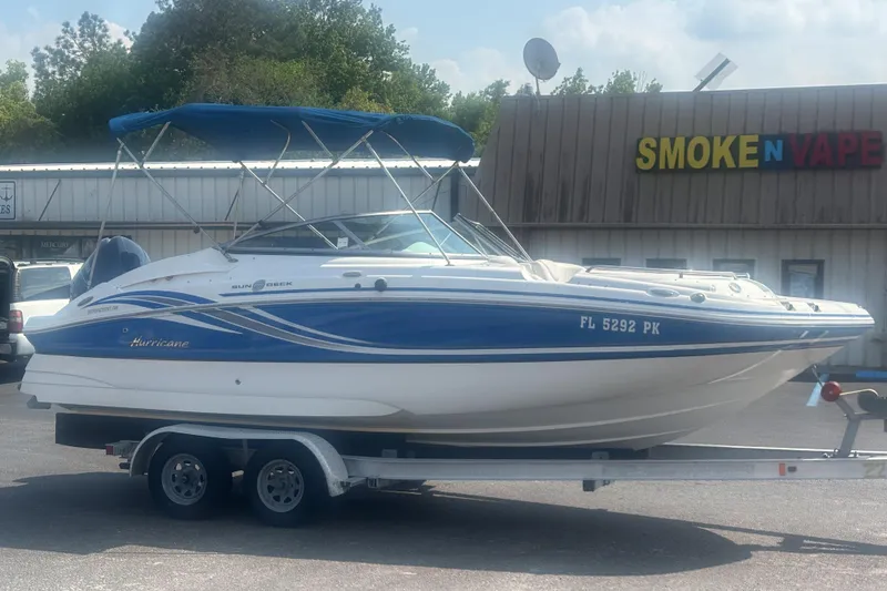 Slide: The Image of 2013 Hurricane SunDeck 2200 DC OB boat on trailer, parked near a store. - 6