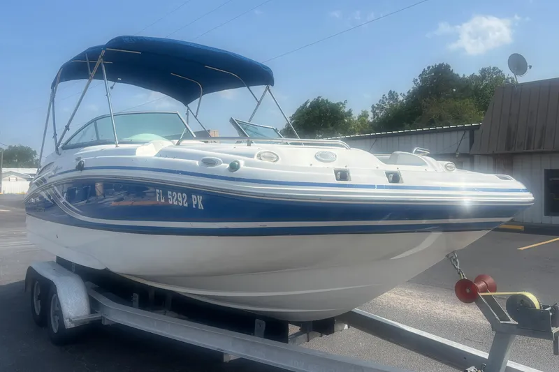 Slide: The Image of 2013 Hurricane SunDeck 2200 DC OB boat on trailer, blue and white design, parked outdoors. - 7