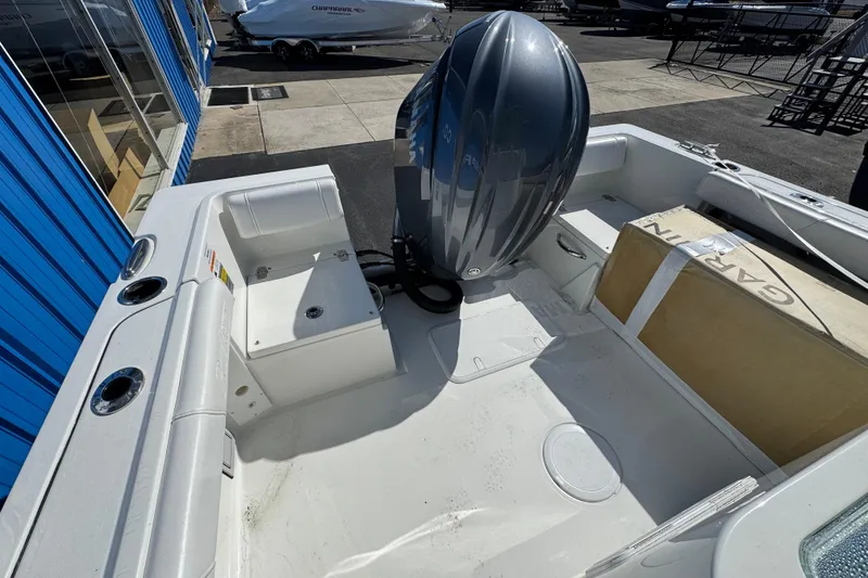 Slide: The Image of 2026 Parker 230 Coastal Elite boat interior with engine and seating, docked near blue building. - 18