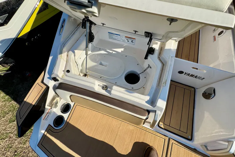 Slide: The Image of 2022 Yamaha Boats 275SD interior storage compartment with open hatch and teak flooring. - 15