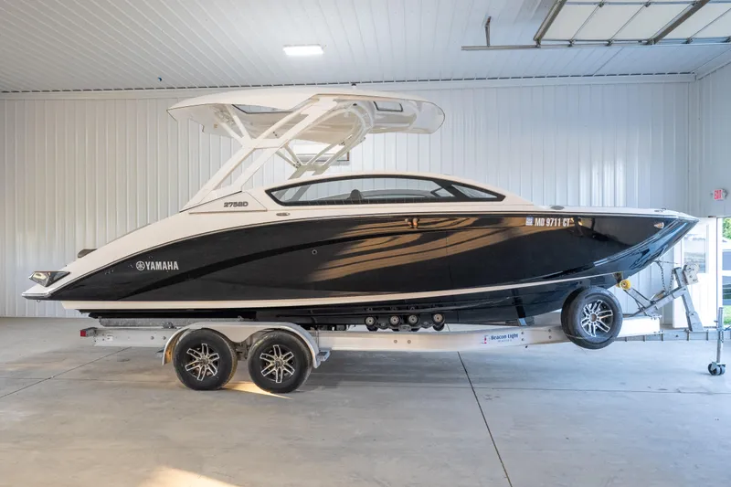 Slide: The Image of 2022 Yamaha Boats 275SD in a garage, black hull, on a trailer. - 2
