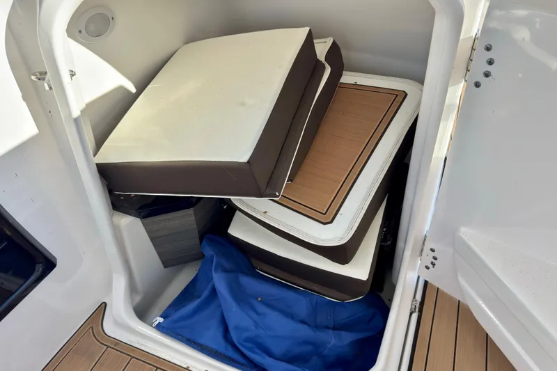 Slide: The Image of Storage compartment in 2022 Yamaha Boats 275SD with cushions and blue cover. - 28
