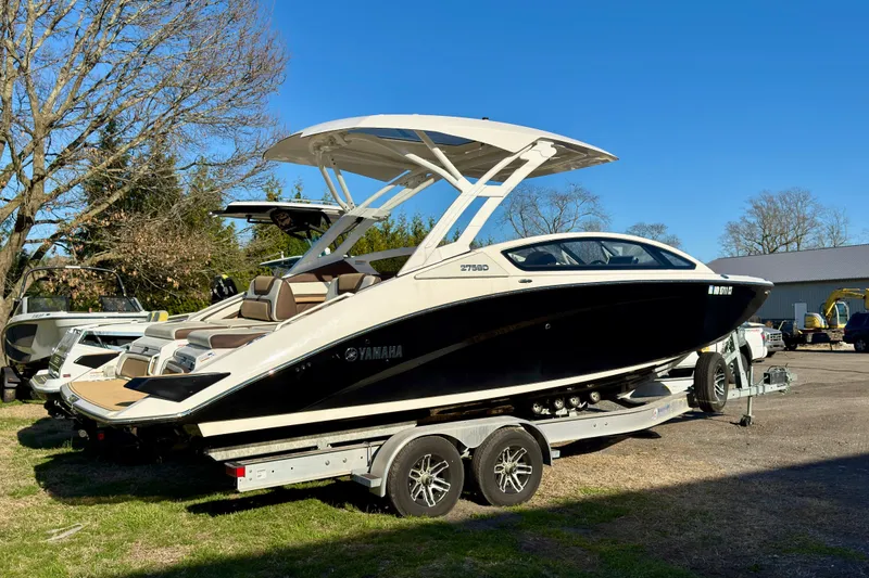 Slide: The Image of 2022 Yamaha Boats 275SD on trailer, sleek design, parked outdoors under clear blue sky. - 9