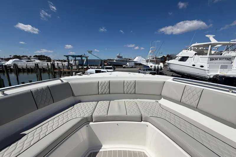 Slide: The Image of 2026 Pursuit S 358 Sport boat with luxurious seating at a marina under a clear blue sky. - 124