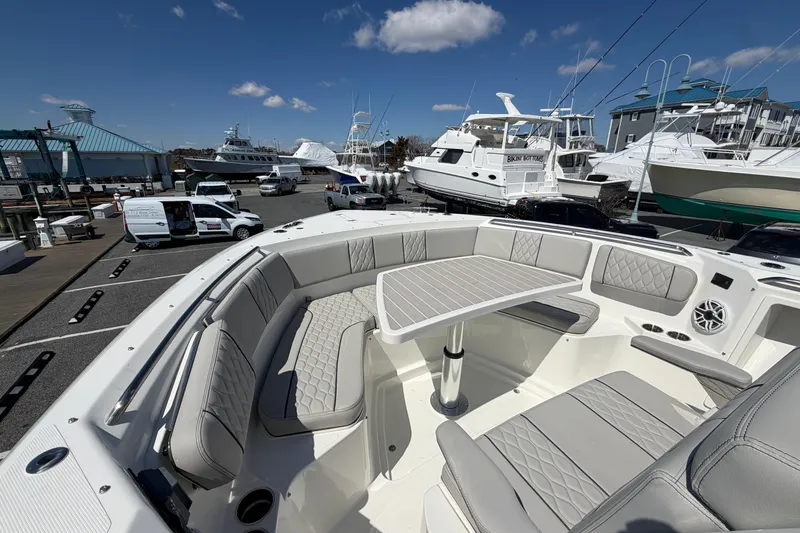 Slide: The Image of 2026 Pursuit S 358 Sport boat with luxurious seating and table, docked at a marina. - 126