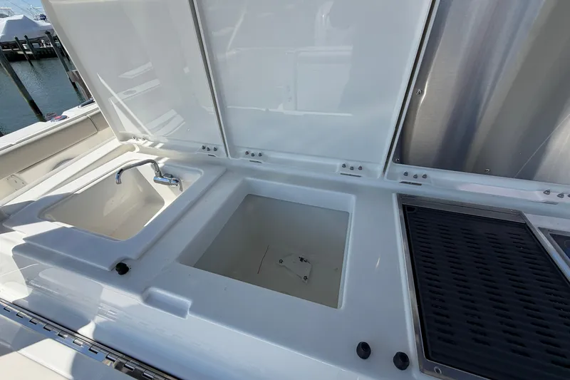 Slide: The Image of 2026 Pursuit S 358 Sport boat sink and storage area with open lids. - 45
