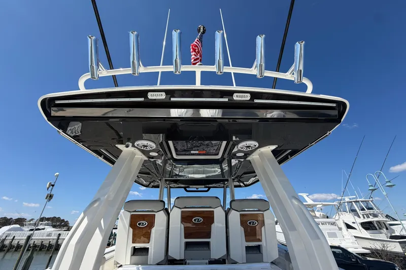 Slide: The Image of 2026 Pursuit S 358 Sport boat with sleek design and rod holders, docked under clear blue sky. - 49