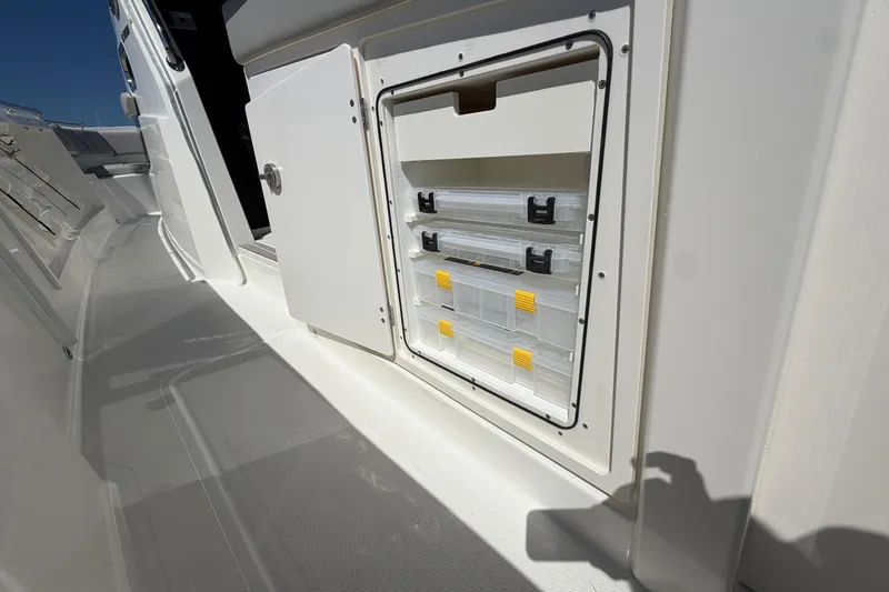 Slide: The Image of Storage compartment on 2026 Pursuit S 358 Sport boat, featuring organized tackle boxes. - 57