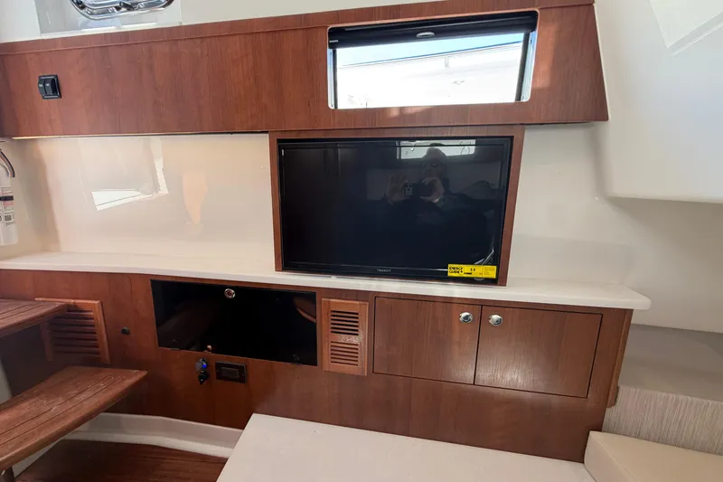 Slide: The Image of Interior of 2026 Pursuit S 358 Sport boat with wooden cabinetry and built-in TV. - 92