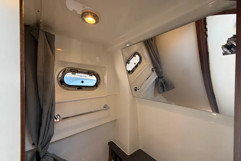 Slide: The Image of Interior of 2026 Pursuit S 358 Sport boat, featuring a window, curtain, and mirror. - 99