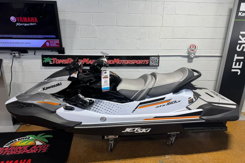Slide: The Image of 2026 Kawasaki STX160LX jet ski displayed indoors at a motorsports showroom. - 5