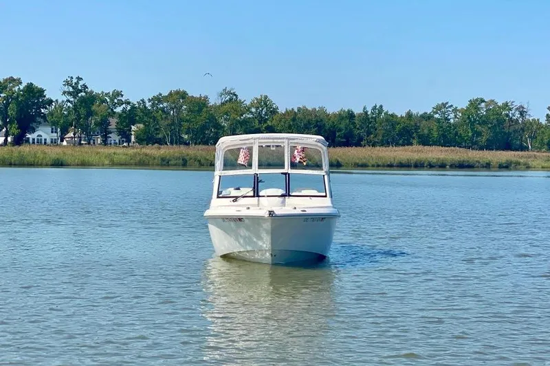 Slide: The Image of 2013 Everglades 230 Dual Console boat on calm water with trees in the background. - 2