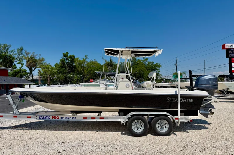 The Image of 2008 ShearWater 2400Z boat on trailer, parked outdoors under clear blue sky. - 0