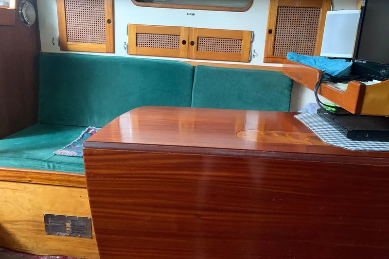 Slide: The Image of Interior of a 1960 Rhodes Bounty boat with green seating and wooden table. - 10