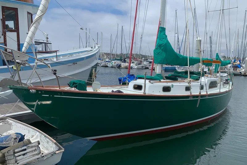 Slide: The Image of Vintage 1960 Rhodes Bounty sailboat docked in a marina, featuring green hull and sails. - 5