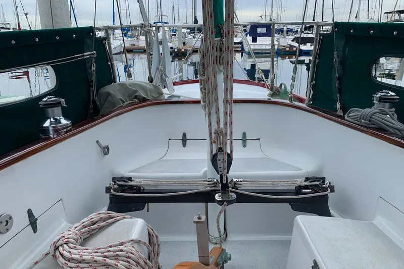 Slide: The Image of Cockpit of a 1960 Rhodes Bounty sailboat, featuring ropes and winches, docked at a marina. - 6