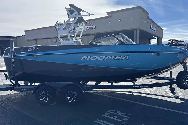 Slide: The Image of 2025 Moomba Craz boat in blue, parked on a trailer outside a building. - 6