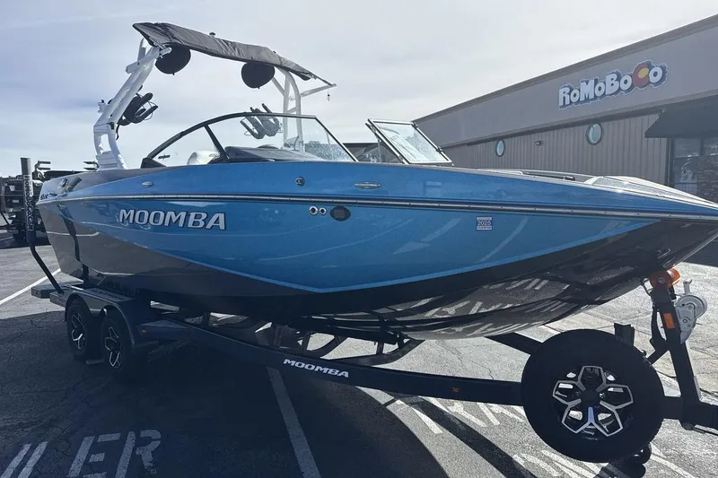 Slide: The Image of 2025 Moomba Craz boat in blue, parked on a trailer outside a building. - 7