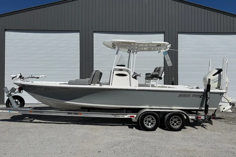 The Image of 2021 Sea Pro 248 Bay boat on trailer, parked in front of a large garage. - 1