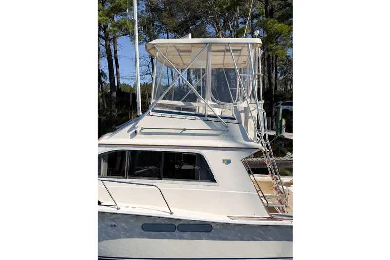 Slide: The Image of 1988 Pacemaker 36 Convertible boat with enclosed flybridge, docked near trees. - 13