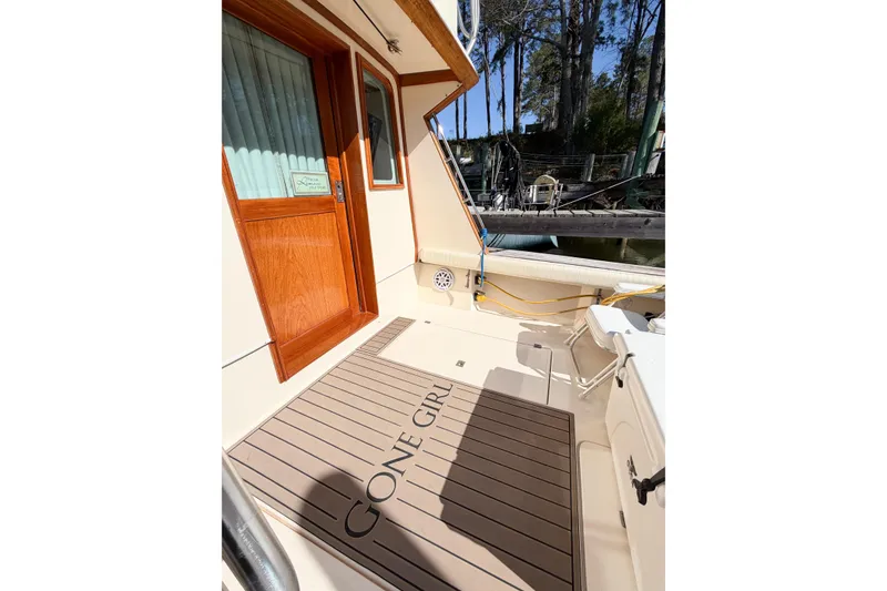 Slide: The Image of 1988 Pacemaker 36 Convertible boat deck with "Gone Girl" mat, docked near trees. - 20