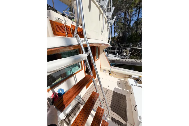 Slide: The Image of 1988 Pacemaker 36 Convertible yacht with wooden steps and metal railings, docked near trees. - 46
