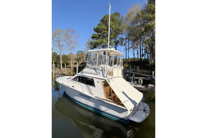 Slide: The Image of 1988 Pacemaker 36 Convertible boat docked in a serene wooded area. - 7