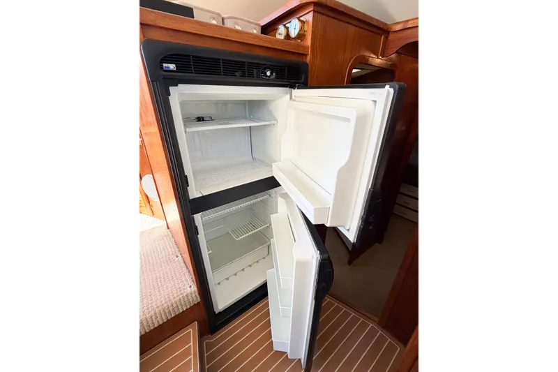 Slide: The Image of Open refrigerator inside 1988 Pacemaker 36 Convertible yacht, showcasing spacious interior and wooden surroundings. - 79