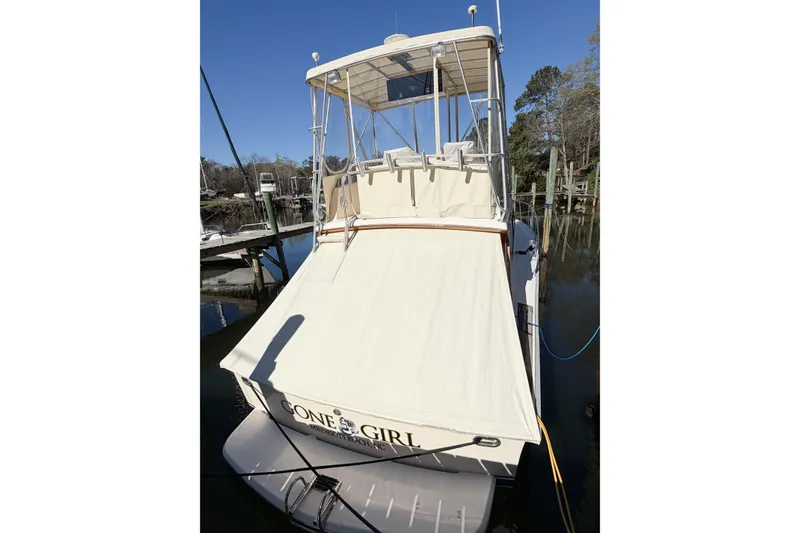 Slide: The Image of 1988 Pacemaker 36 Convertible boat docked, featuring a beige canopy and clear blue sky. - 8