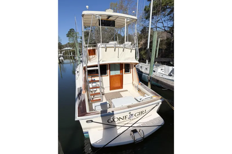 Slide: The Image of 1988 Pacemaker 36 Convertible boat docked, rear view, named "Gone Girl," in a serene marina setting. - 9